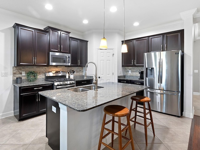 kitchen featuring appliances with stainless steel finishes, a sink, dark stone countertops, and light tile patterned floors