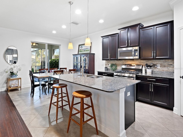 kitchen with stainless steel appliances, a sink, visible vents, backsplash, and a kitchen bar