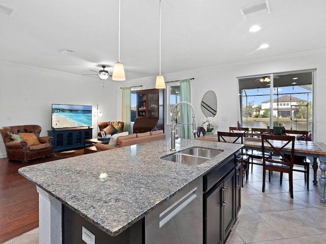 kitchen with decorative light fixtures, visible vents, open floor plan, a sink, and dishwasher