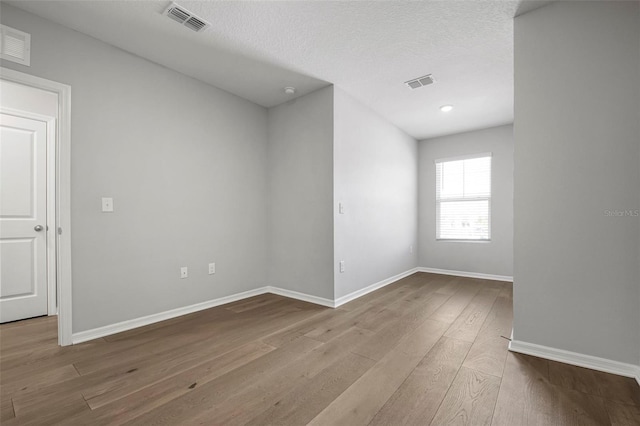 spare room with light hardwood / wood-style floors and a textured ceiling