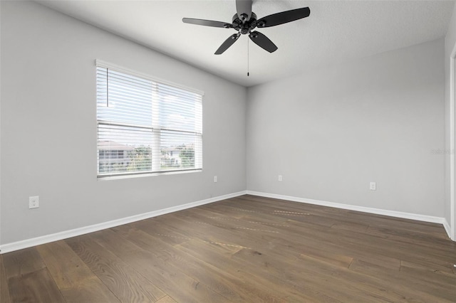 empty room with ceiling fan and dark hardwood / wood-style flooring