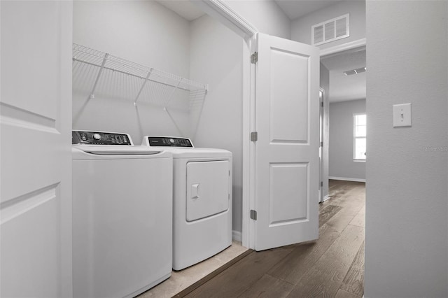 clothes washing area with dark hardwood / wood-style flooring and washer and dryer