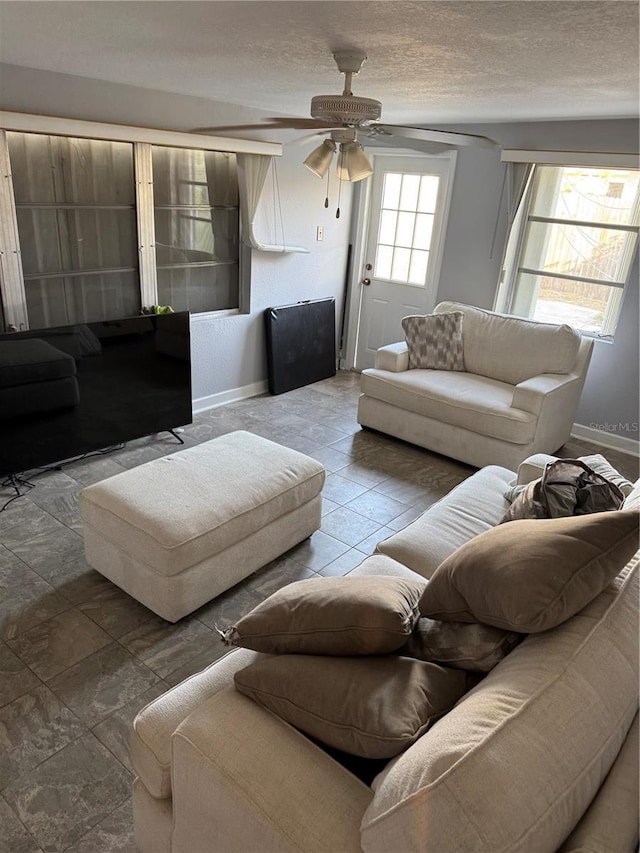 living room with ceiling fan and a textured ceiling