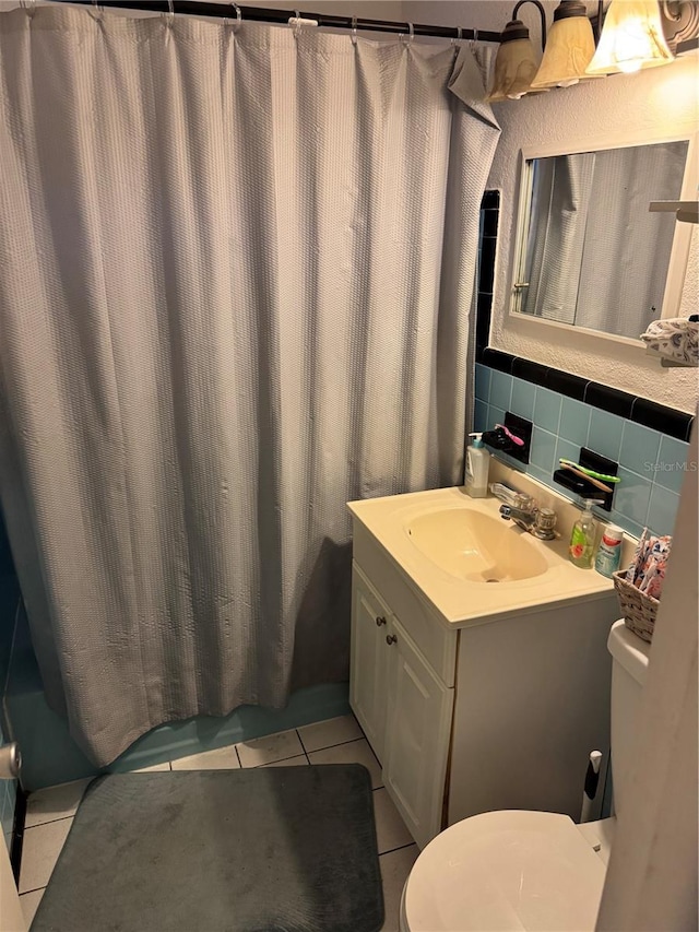 bathroom with tile patterned flooring, vanity, tasteful backsplash, and toilet