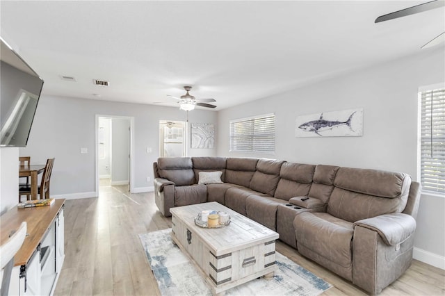 living room with a wealth of natural light, light hardwood / wood-style floors, and ceiling fan