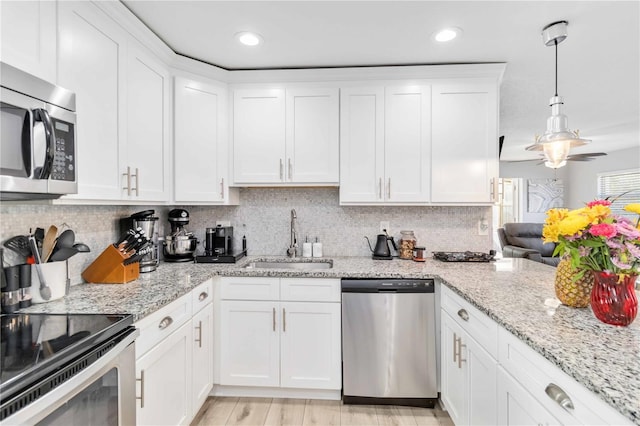 kitchen with sink, white cabinetry, decorative light fixtures, appliances with stainless steel finishes, and decorative backsplash