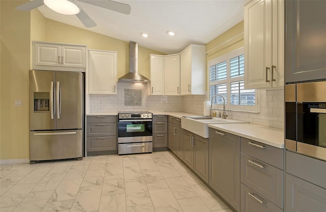 kitchen featuring wall chimney exhaust hood, sink, gray cabinets, stainless steel appliances, and white cabinets