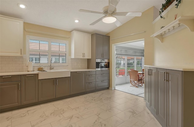 kitchen featuring sink, gray cabinetry, stainless steel oven, vaulted ceiling, and ceiling fan