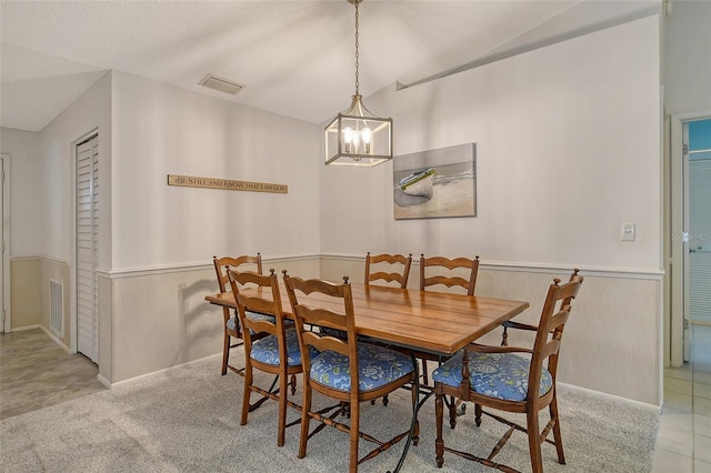 dining room with a notable chandelier, light tile patterned floors, and vaulted ceiling