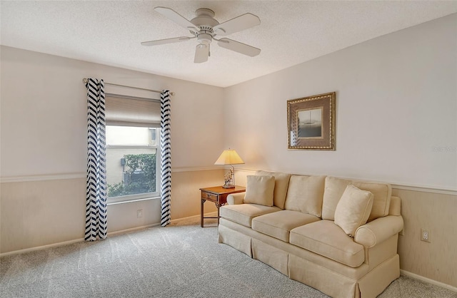 living room featuring ceiling fan, light colored carpet, and a textured ceiling