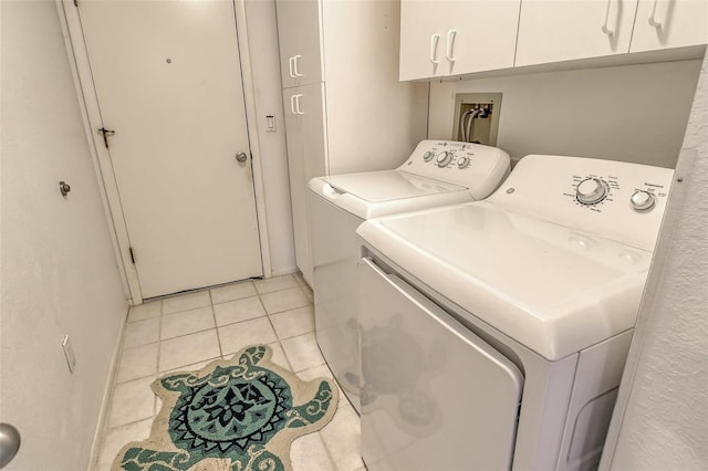 laundry area with light tile patterned floors, cabinets, and washing machine and clothes dryer