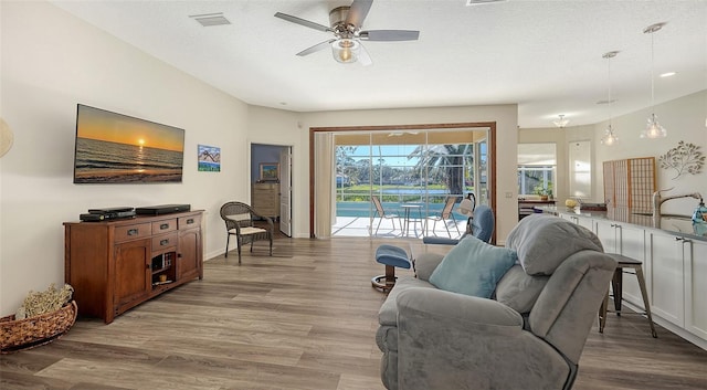 living room featuring ceiling fan, sink, light hardwood / wood-style floors, and a textured ceiling