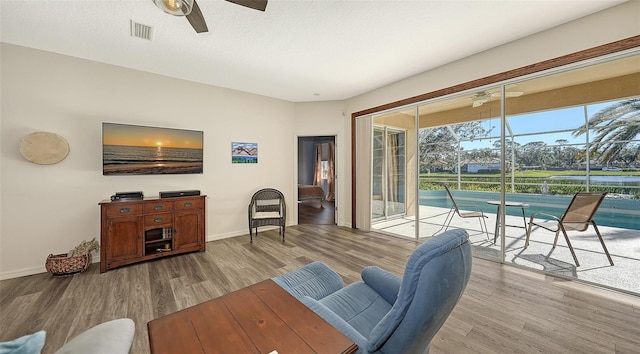 living room with a textured ceiling, light hardwood / wood-style flooring, and ceiling fan