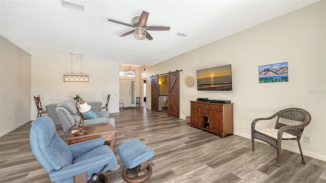 living room featuring lofted ceiling, wood-type flooring, a barn door, and ceiling fan