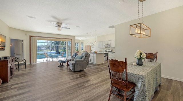 dining room featuring wood-type flooring, sink, ceiling fan with notable chandelier, and a textured ceiling