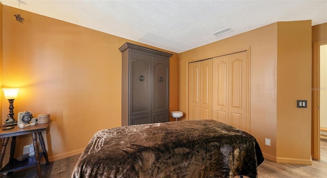 bedroom featuring light hardwood / wood-style floors, a closet, and a textured ceiling