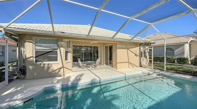 view of swimming pool with ceiling fan, glass enclosure, and a patio