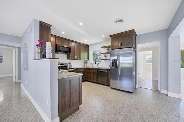 kitchen with dark brown cabinetry, sink, appliances with stainless steel finishes, light stone countertops, and decorative backsplash