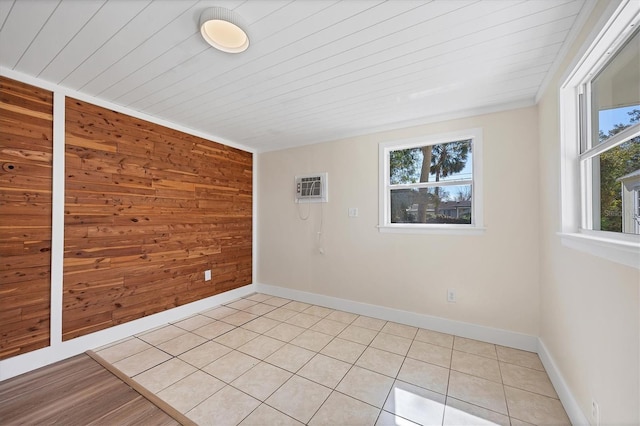 empty room with light tile patterned flooring, a healthy amount of sunlight, a wall mounted AC, and wood walls