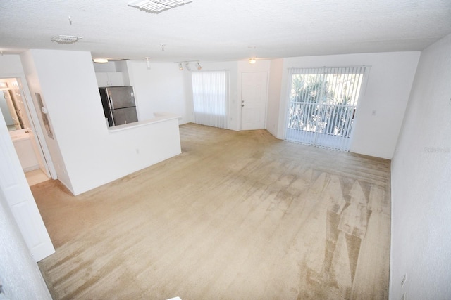 unfurnished living room with light colored carpet and a textured ceiling