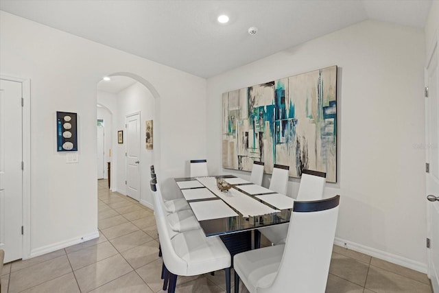 dining space featuring light tile patterned floors and vaulted ceiling