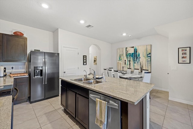 kitchen with dark brown cabinetry, sink, a center island with sink, light tile patterned floors, and stainless steel appliances