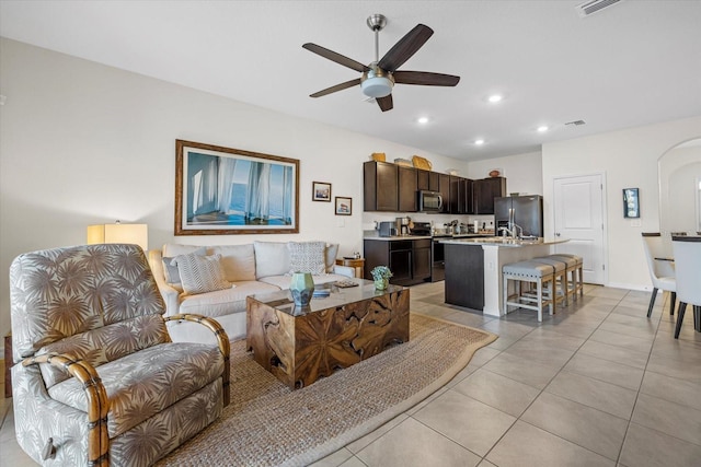 living room featuring light tile patterned flooring, sink, and ceiling fan