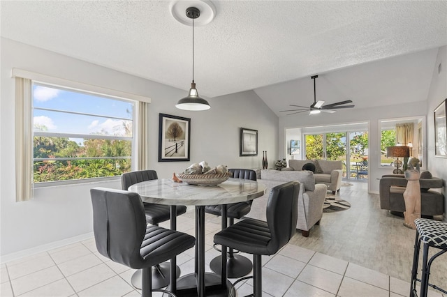 dining area featuring vaulted ceiling, a textured ceiling, and light tile patterned flooring