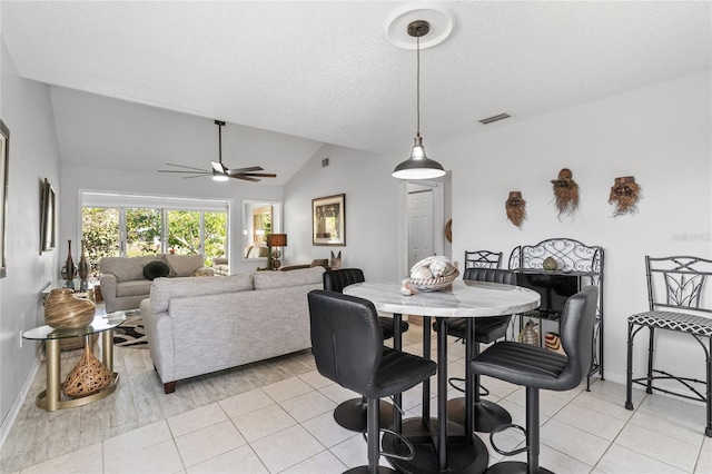 tiled dining space with ceiling fan, lofted ceiling, and a textured ceiling