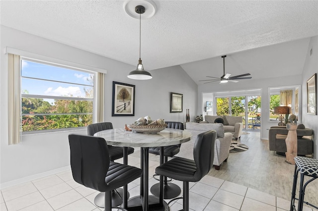 dining room featuring ceiling fan, lofted ceiling, light tile patterned floors, and a textured ceiling