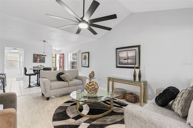 living room featuring vaulted ceiling, a textured ceiling, and light wood-type flooring