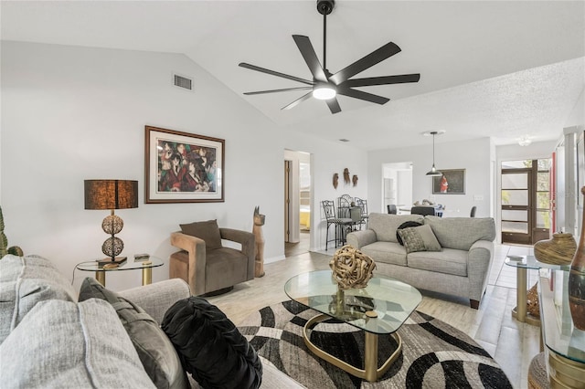 living room featuring ceiling fan, lofted ceiling, light hardwood / wood-style floors, and a textured ceiling