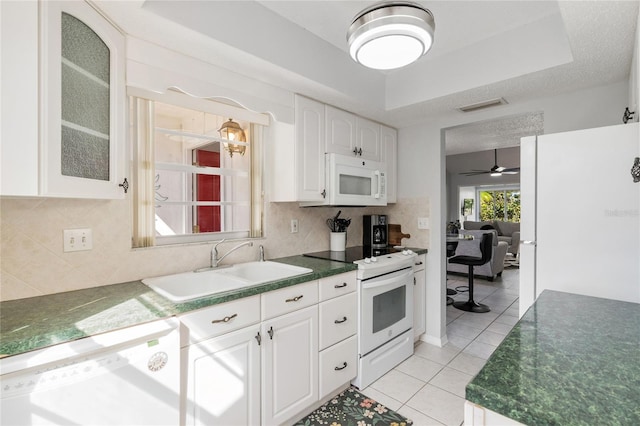 kitchen featuring sink, backsplash, white cabinets, light tile patterned floors, and white appliances