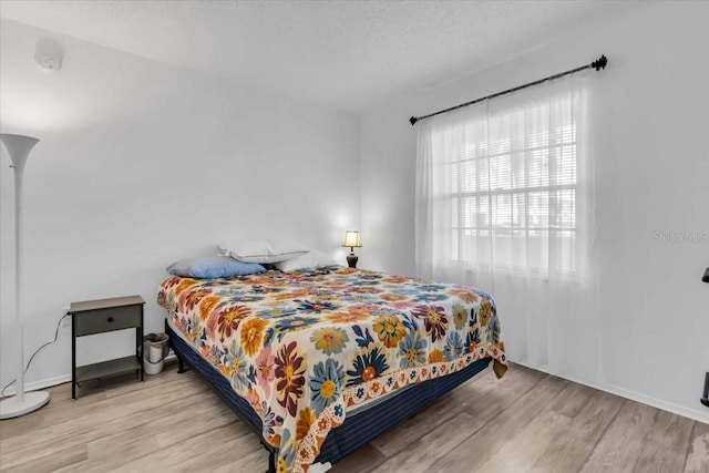 bedroom featuring light hardwood / wood-style floors and a textured ceiling