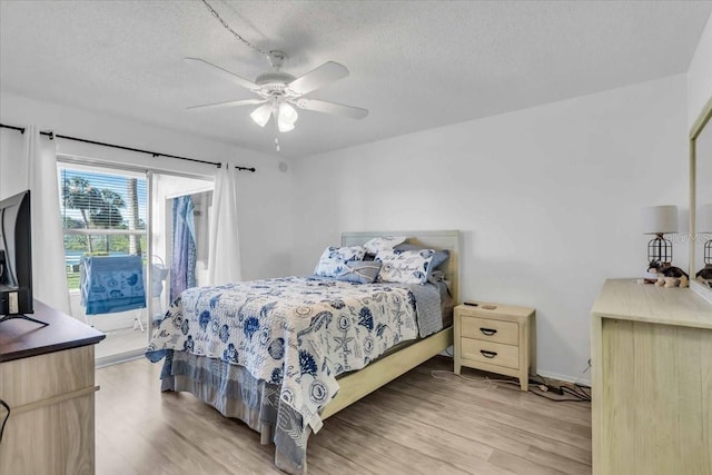 bedroom with light hardwood / wood-style flooring, a textured ceiling, and access to outside