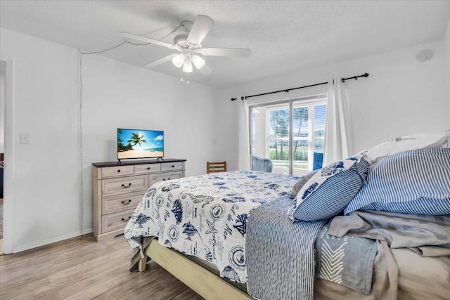 bedroom featuring ceiling fan, light hardwood / wood-style flooring, a textured ceiling, and access to outside