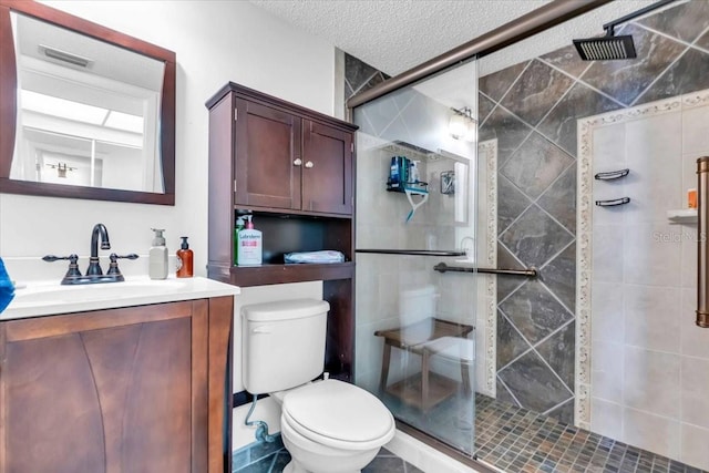 bathroom with toilet, vanity, a textured ceiling, and a shower with shower door