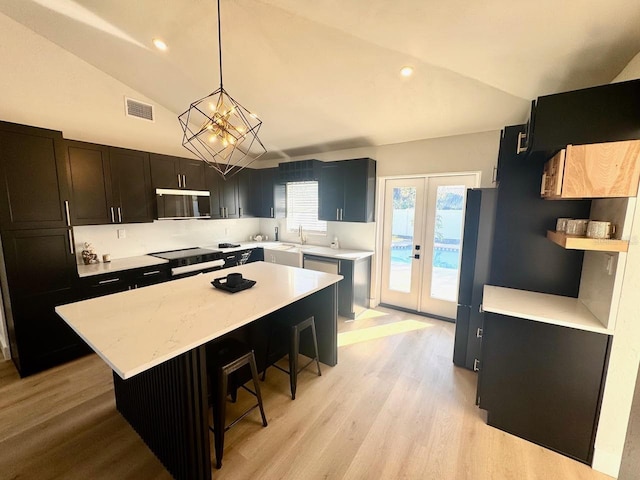 kitchen with decorative light fixtures, black appliances, a center island, and french doors