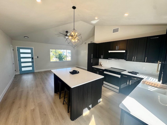 kitchen featuring a center island, vaulted ceiling, hanging light fixtures, light wood-type flooring, and stainless steel electric stove