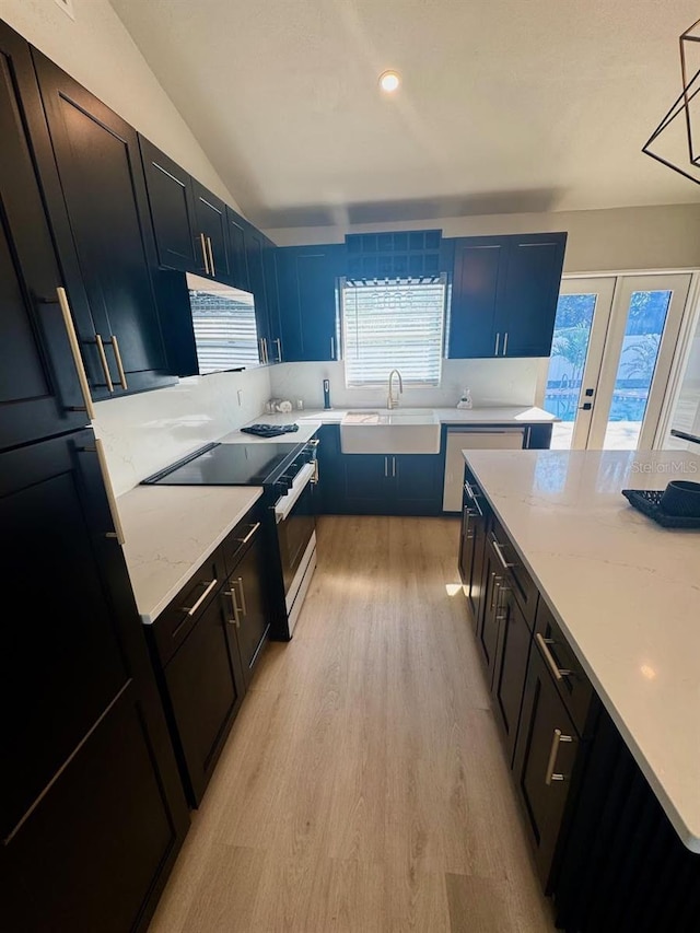 kitchen with stainless steel electric stove, decorative light fixtures, sink, light stone countertops, and light hardwood / wood-style flooring