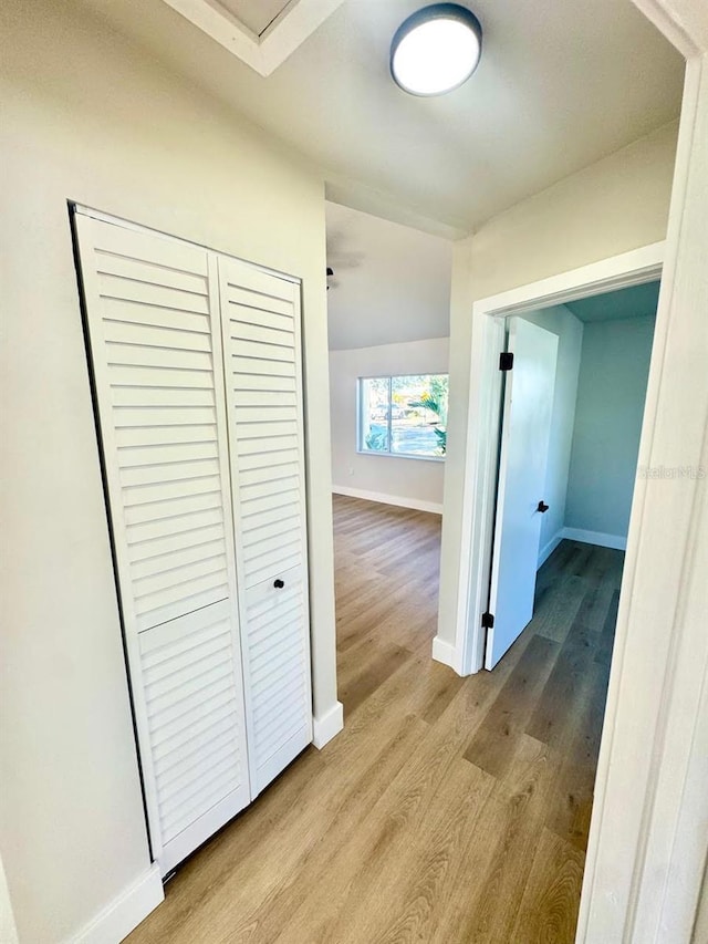 hall with lofted ceiling and light hardwood / wood-style flooring