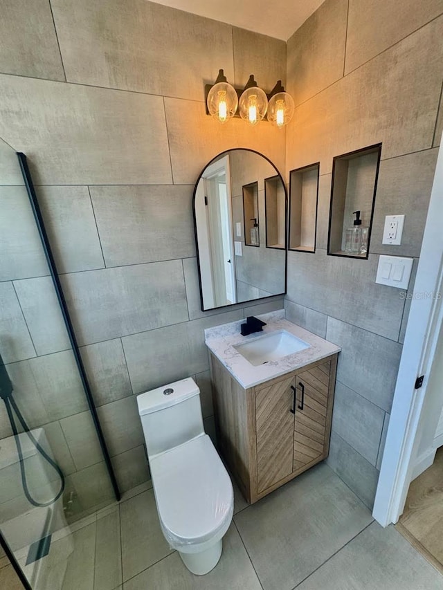 bathroom featuring tile walls, vanity, tile patterned flooring, and toilet