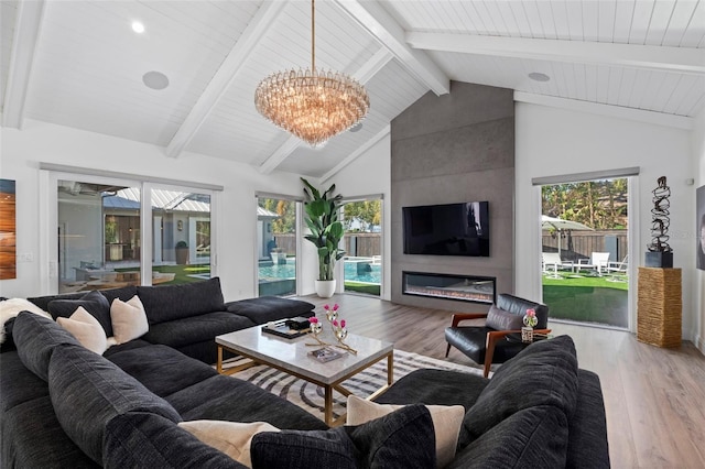 living room featuring beam ceiling, a wealth of natural light, a notable chandelier, and light hardwood / wood-style floors