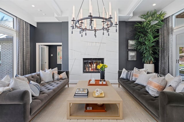 living room featuring beam ceiling, a tile fireplace, and a notable chandelier