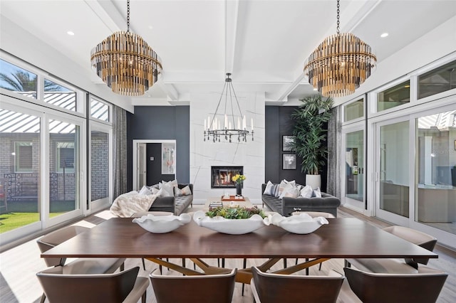 sunroom / solarium featuring beam ceiling, a premium fireplace, and a chandelier