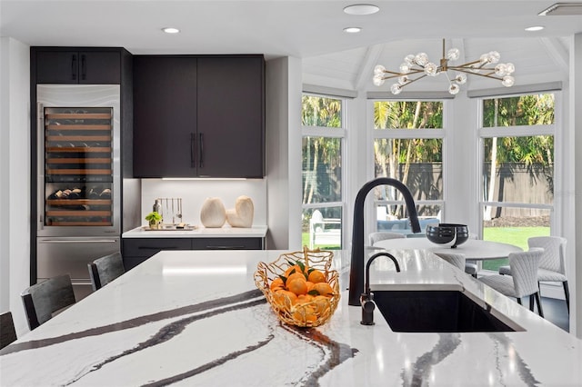 kitchen featuring light stone counters, beverage cooler, a breakfast bar, and sink