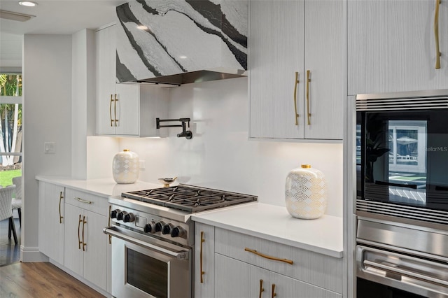 kitchen featuring appliances with stainless steel finishes, exhaust hood, and light hardwood / wood-style flooring