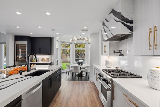 kitchen with sink, light hardwood / wood-style flooring, pendant lighting, stainless steel appliances, and white cabinets