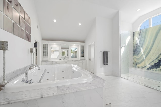 bathroom featuring tiled bath and high vaulted ceiling