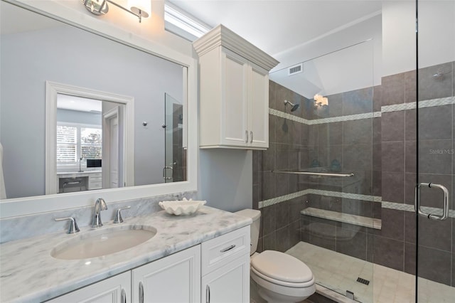 bathroom featuring vanity, a shower with shower door, and toilet